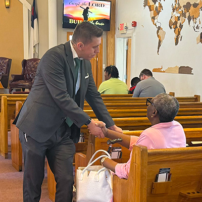 Pastor Middleton greeting church member with handshake before Sunday morning service