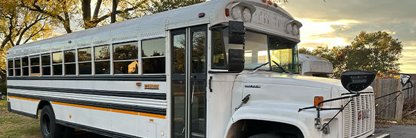 White school bus used for Calvary Bible Baptist Church bus ministry parked outside at sunset