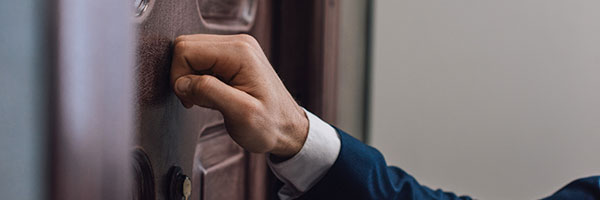 Hand in suit knocking on wooden door