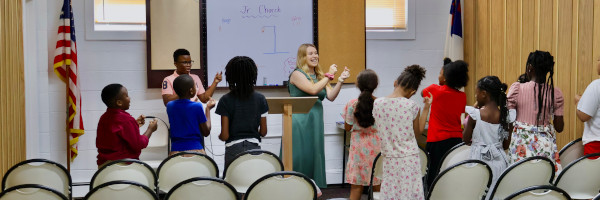 Teacher leading interactive Bible lesson with children in classroom during Junior Church